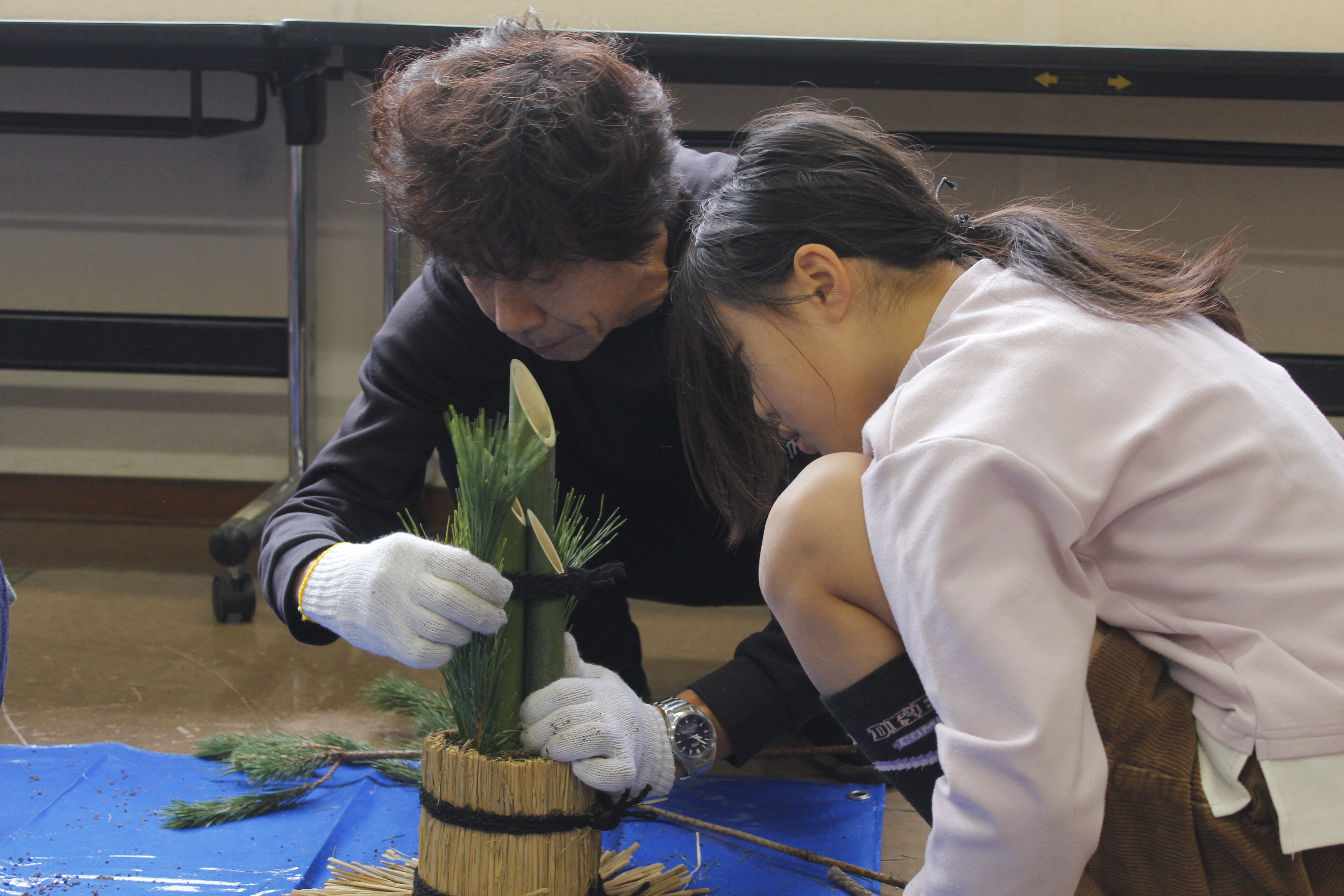 土台に松の枝を挿す小学生と保護者